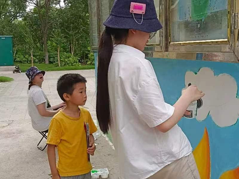图为团队成员与社区小朋友一起进行绘画